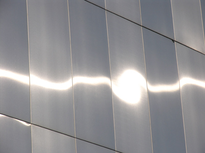 The sun on a stainless steel building.  It must get hot in the summer.