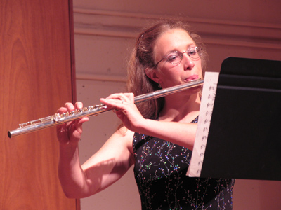 The week I got my camera I tried to photograph this flutist but they came out blurry, so I settled for a picture of her flowers (see May 27, 2004).  Since then I`ve learned a thing or two, and this picture is clear enough to see that the music is in F-major and 9/8 time.