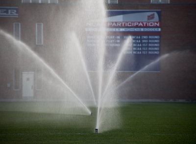 The mystical alignment of soccer field sprinklers at sunrise.