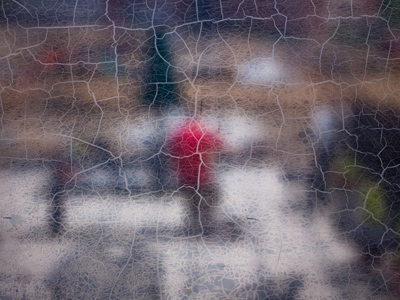 Some guy sitting at a picnic table wearing a red shirt -- seen through a really freaky window.