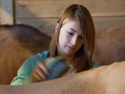 She works hard grooming the horses, but isn`t allowed to take them on a trail ride because she`s still too young.