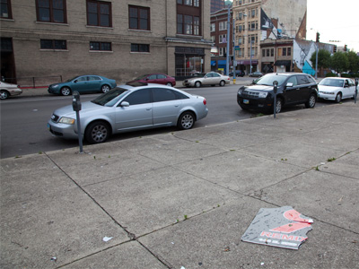 The broken piece of sign on the ground belongs on the building across the street.