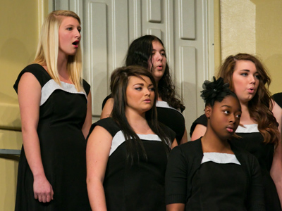 The blonde girl sang a solo.  The choir director got her name wrong.  He was loudly corrected by the whole choir.