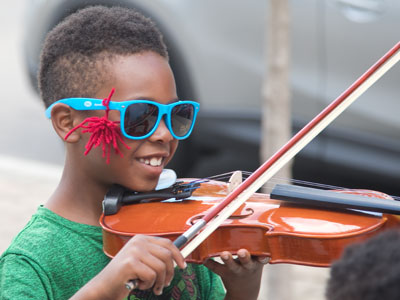 Trying out a violin at the instrument petting zoo.