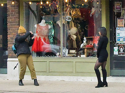 The photographer wears a coat while the model shivers.
